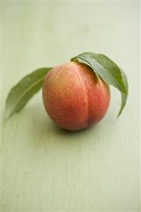 Nectarine with leaves on green background