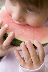 Child biting into watermelon