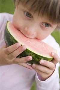 Child biting into watermelon