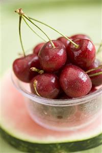 Cherries in plastic tub on slice of watermelon