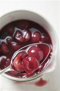 Cherry compote in pan and on spoon