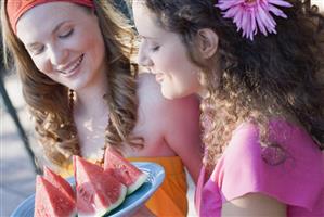 Two young women with wedges of watermelon