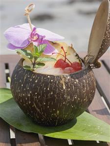 Coconut drink with pineapple, cocktail cherry and orchid