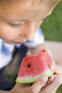 Small boy eating a piece of watermelon