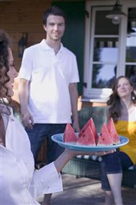 Woman serving watermelon wedges at a garden party