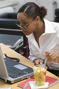 Woman eating fruit salad in the office