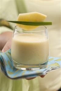 Woman serving a glass of mango lassi (India)