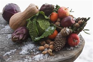 Still life: apples, vegetables, nuts & cones on wooden table