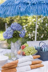 Baguettes and fruit on table laid out of doors