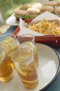 Iced tea, chips and hamburgers on table out of doors