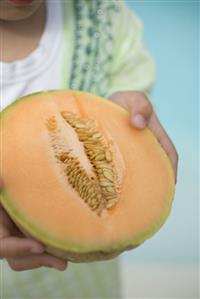 Child holding half a cantaloupe melon