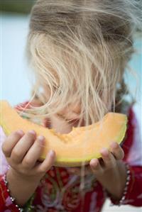 Small girl eating a slice of melon