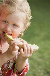 Small girl eating a slice of melon