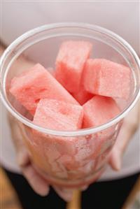 Woman holding plastic tub of diced watermelon