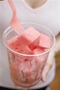 Woman eating diced watermelon out of plastic tub