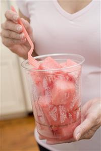 Woman eating diced watermelon out of plastic tub