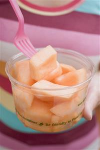 Woman eating diced melon out of plastic tub