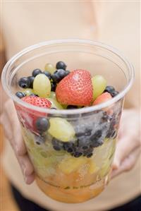 Woman holding plastic tub of fruit salad