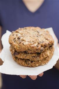 Woman holding large chocolate chip cookies on paper