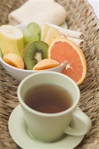 Cup of tea, fresh fruit and towel in basket