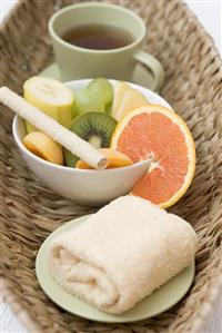 Cup of tea, fresh fruit and towel in basket