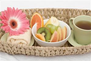 Cup of tea, fresh fruit, towel and flower in basket