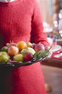 Woman holding bowl of fruit (Christmas)