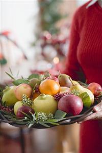 Woman holding bowl of fruit (Christmas)