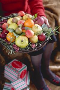 Woman holding bowl of fruit (Christmas)