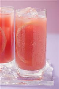 Two glasses of pink grapefruit juice with ice cubes