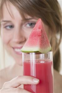 Woman holding glass of watermelon juice with watermelon wedge