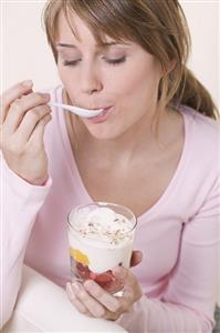 Woman eating yoghurt muesli with fruit