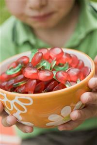 Small boy holding bowl of cherry jelly sweets