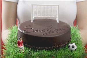 Woman holding Sacher torte with football figure & football