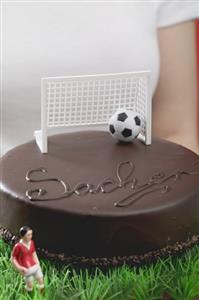 Woman holding Sacher torte with football figure & football