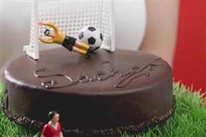 Woman holding Sacher torte with football figures