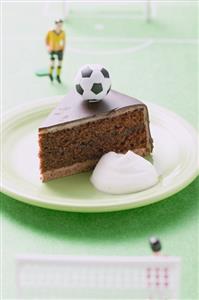 Piece of Sacher torte with cream, football & football figure