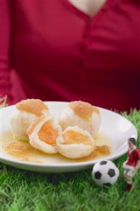 Woman serving apricot dumplings with football figure & football