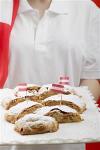 Woman holding several pieces of apple strudel on tray (Austria)