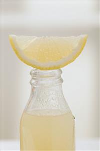 Lemon juice in bottle with fresh lemon wedge