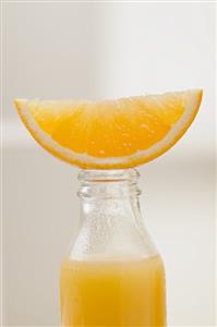 Orange juice in bottle with fresh orange wedge