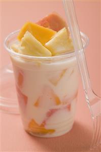 Yoghurt with fresh fruit in plastic pot, fork beside it