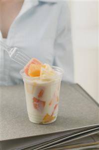 Woman eating fruit yoghurt in office