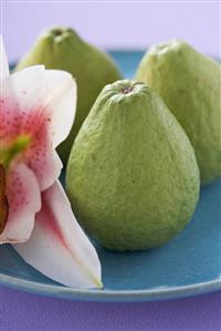 Three guavas on plate with orchid