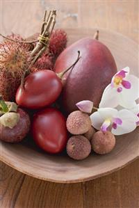 Assorted exotic fruits in a dish with orchids