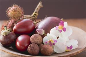 Assorted exotic fruits in a dish with orchids