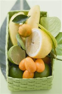 Citrus fruit and bananas in green basket