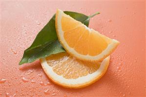 Orange wedge, orange slice and leaf with drops of water