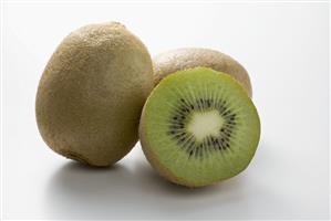 Half a kiwi fruit in front of two whole kiwi fruits