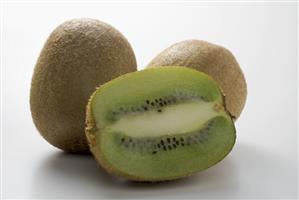 Half a kiwi fruit in front of two whole kiwi fruits